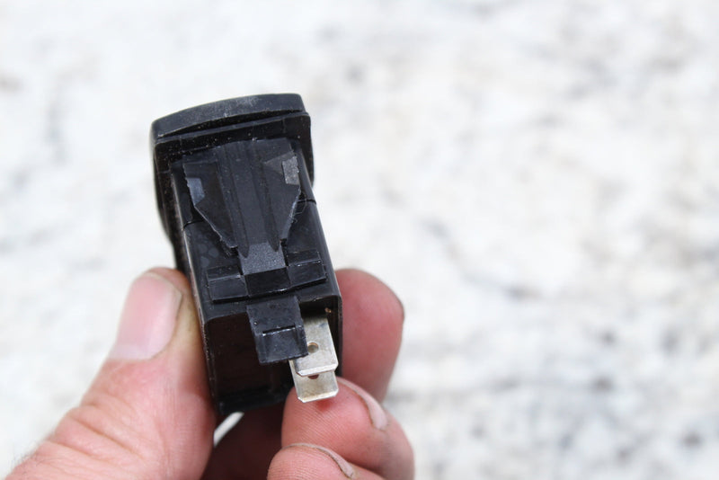 Black rocker switch with metal terminals.