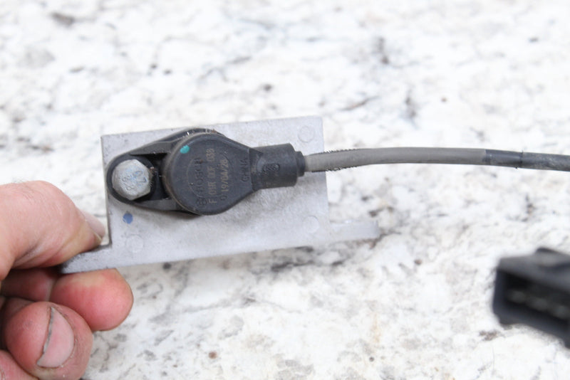 Gray sensor with mounting bracket and wire.