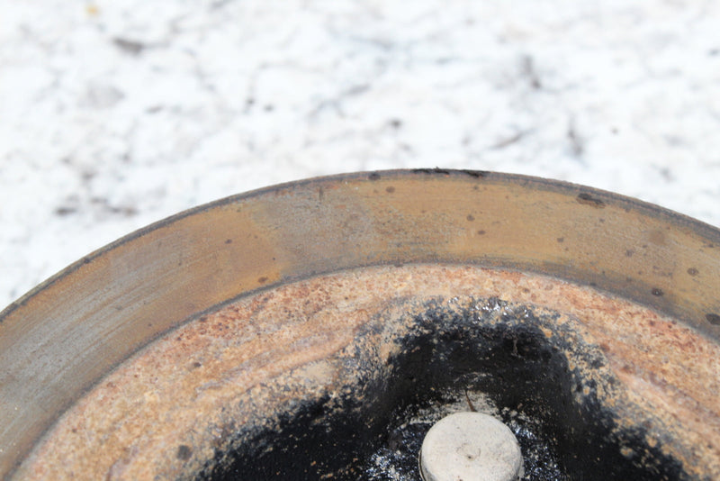 Worn, metallic, circular object.
