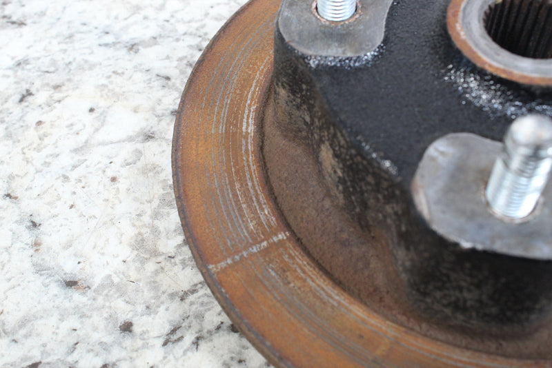 Rusted, grooved brake rotor with attached hub.